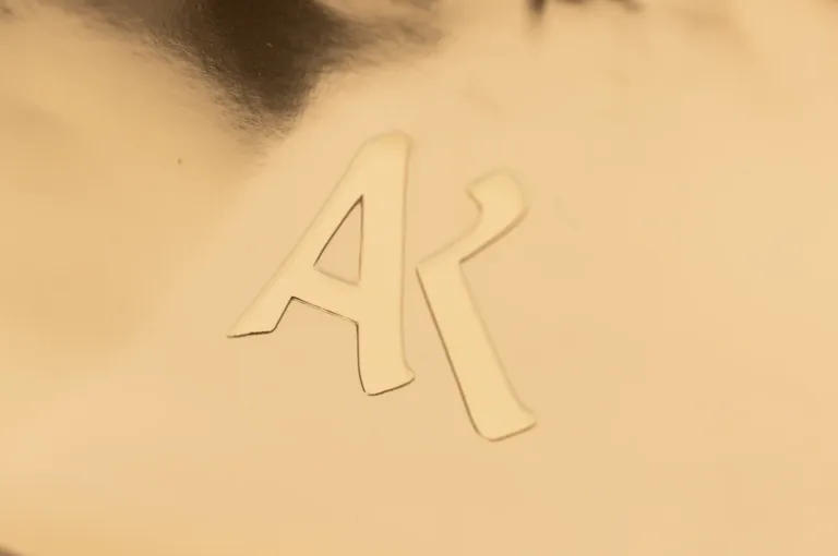 Wytłoczony monogram AR na złotej powierzchni